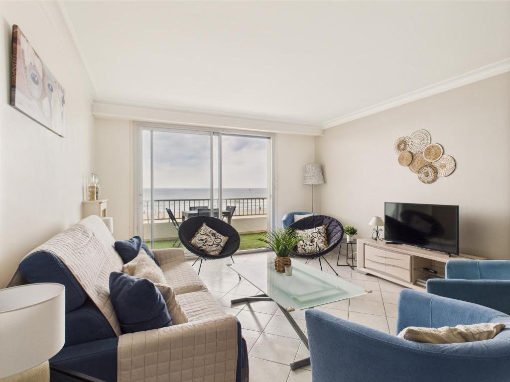 un salon avec un canapé, des chaises et une télévision dans l'établissement Vue mer - Appartement pour 6 - 5 m de la plage, à Pornichet