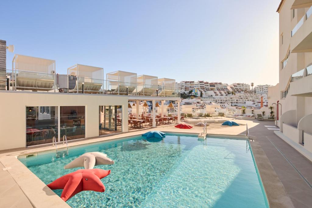 a swimming pool with two people in a building at Hotel Indigo Albufeira by IHG in Albufeira