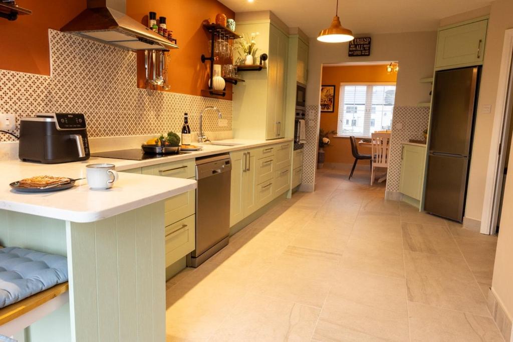 a kitchen with orange walls and white counter tops at Sarahs Home Away from Home Luxury Apartment in Ennis