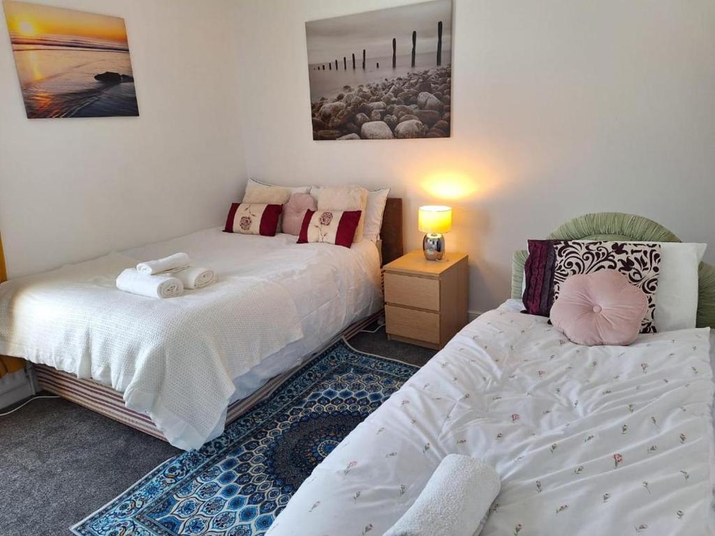 a bedroom with two beds and a table with a lamp at 12 Cornwallis Lodge Family Room 1 in Stoke on Trent