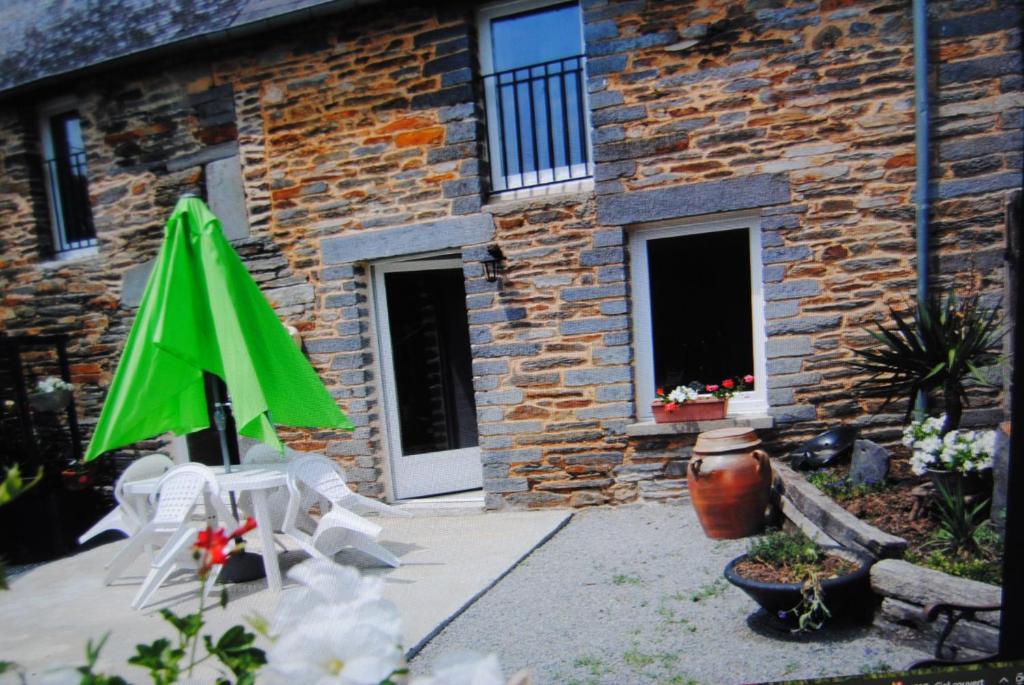 un patio avec un parasol vert et des chaises devant un bâtiment dans l'établissement maison de campagne, à La Celle-sous-Gouzon