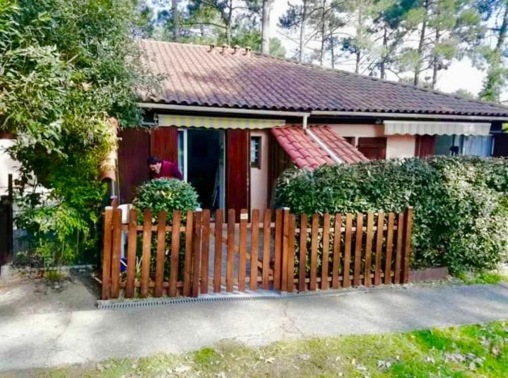 une maison avec une clôture en bois devant elle dans l'établissement Maisonnette au cœur des pins, à Lacanau