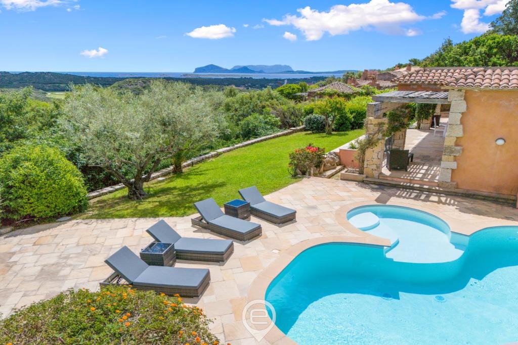 an outdoor swimming pool with lounge chairs and a house at Villa Cereseto in Abbiadori