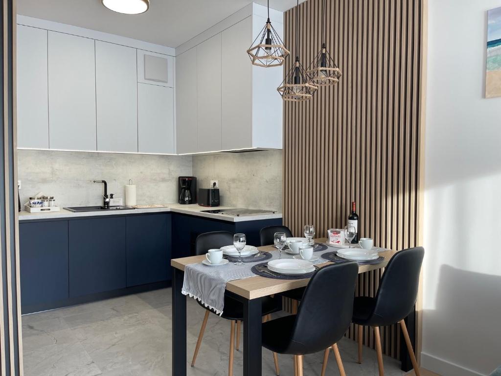 eine Küche mit einem Tisch und Stühlen sowie eine Küche mit weißen Schränken in der Unterkunft Zakręcona Fala Let's Sea Gąski in Gąski