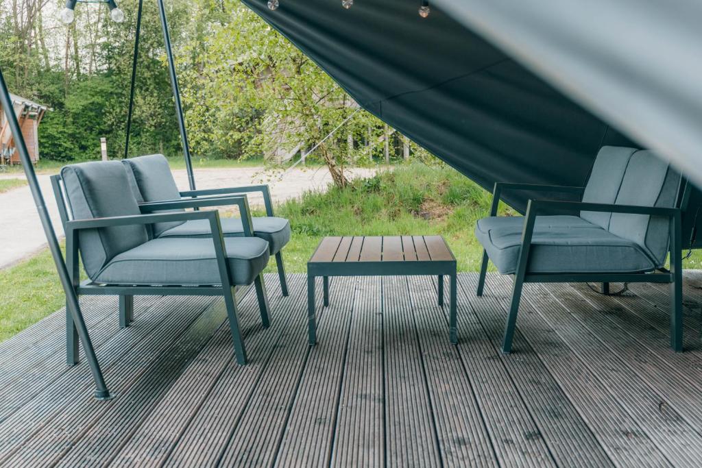 two chairs and a table on a deck at Glamping bij Vakantiepark De Sallandshoeve in Nieuw-Heeten