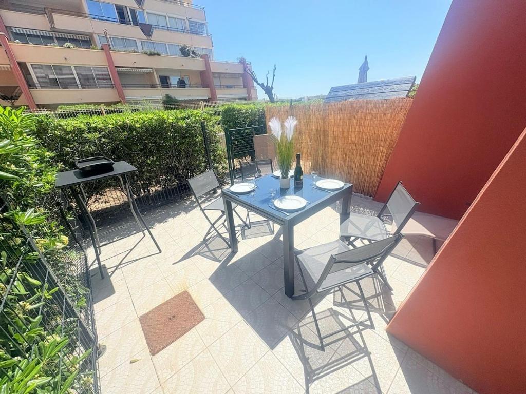 un patio avec une table et des chaises et une clôture dans l'établissement Le Toucan, Front de mer -1 min des plages, à Sète