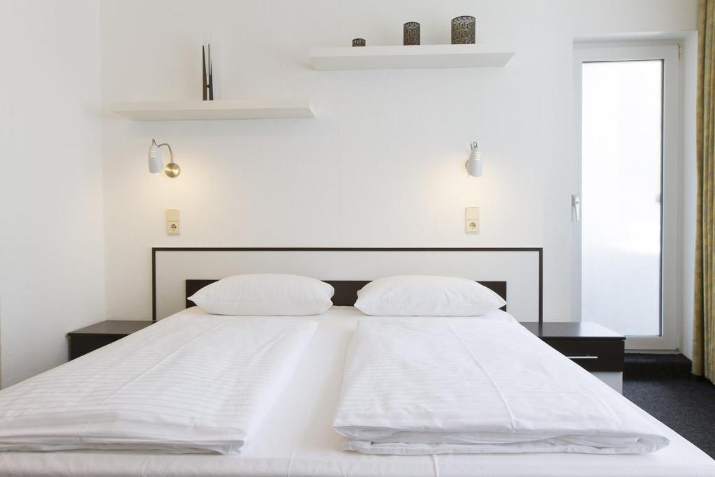 a white bed with two white pillows on it at Aparthotel VEGA in Berlin