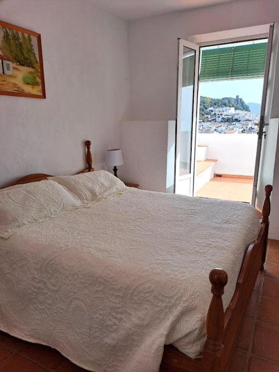 a bedroom with a bed with a view of a balcony at Casa Sinclair in Gaucín