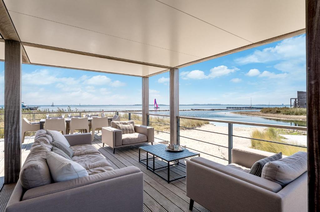 a living room with couches and a view of the beach at Villa Super VIP | 4 Pers. (Villa 3) met privéstrand in Ouddorp
