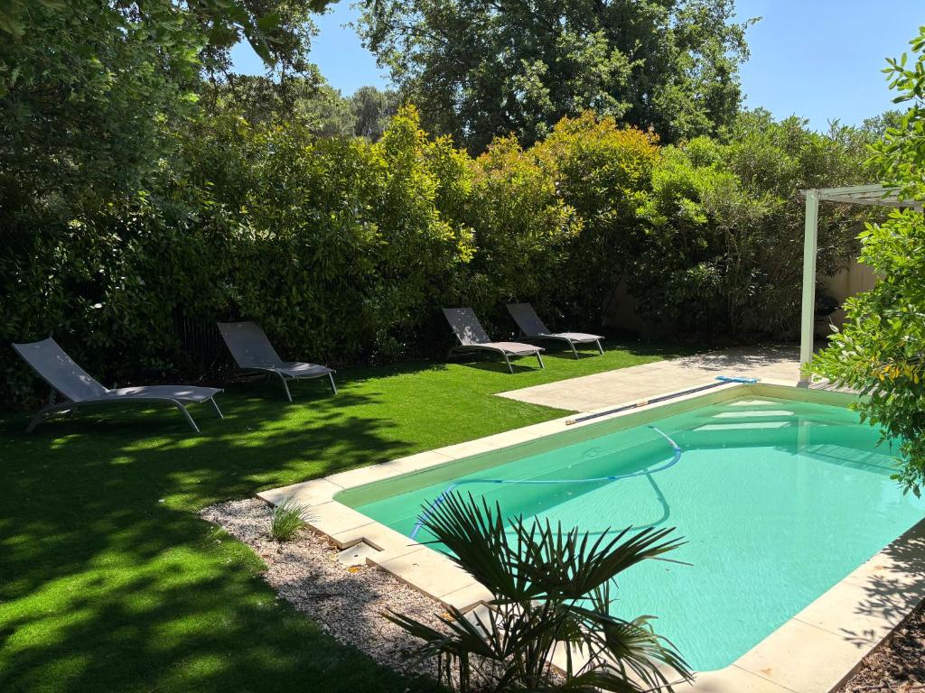 a swimming pool in a yard with two lawn chairs at Les Jardins du Castelas - Domaine et Spas in Uchaux