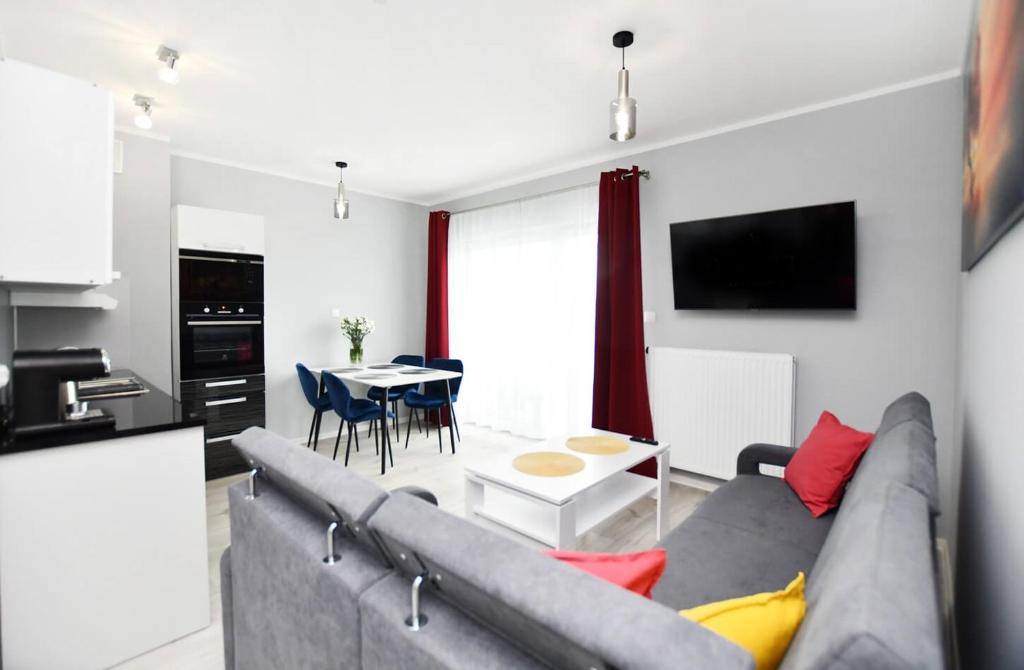 a living room with a gray couch and a table at Apartament Black Sunset Resort SurfingBird Grzybowo in Grzybowo
