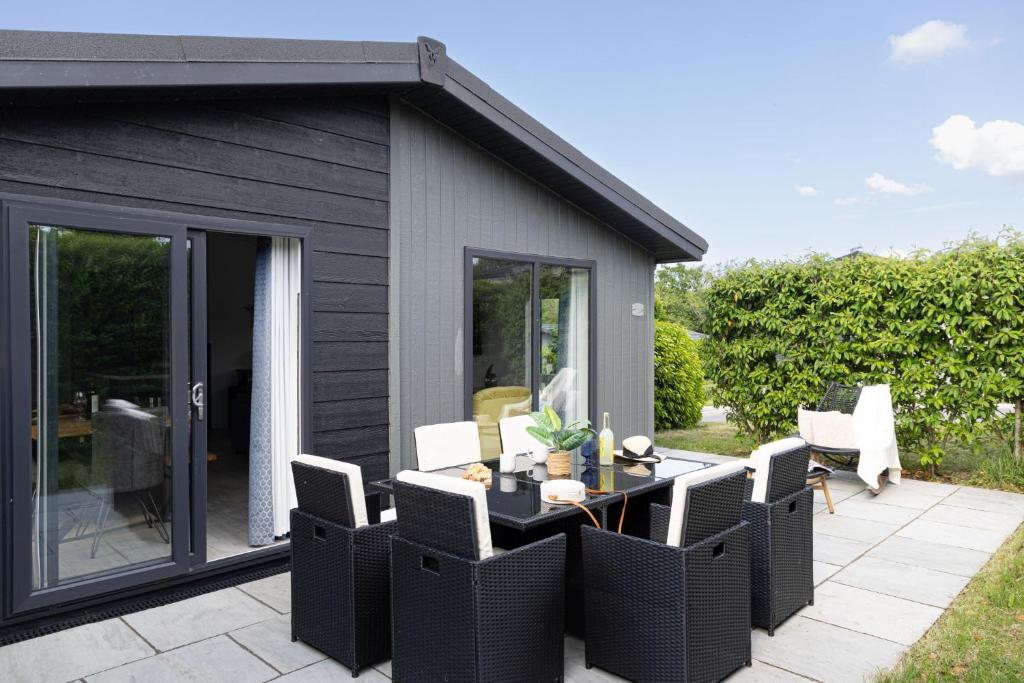 a patio with a table and chairs and a house at Bluebell Lodge, 29 Roadford Lake Lodges in Lifton