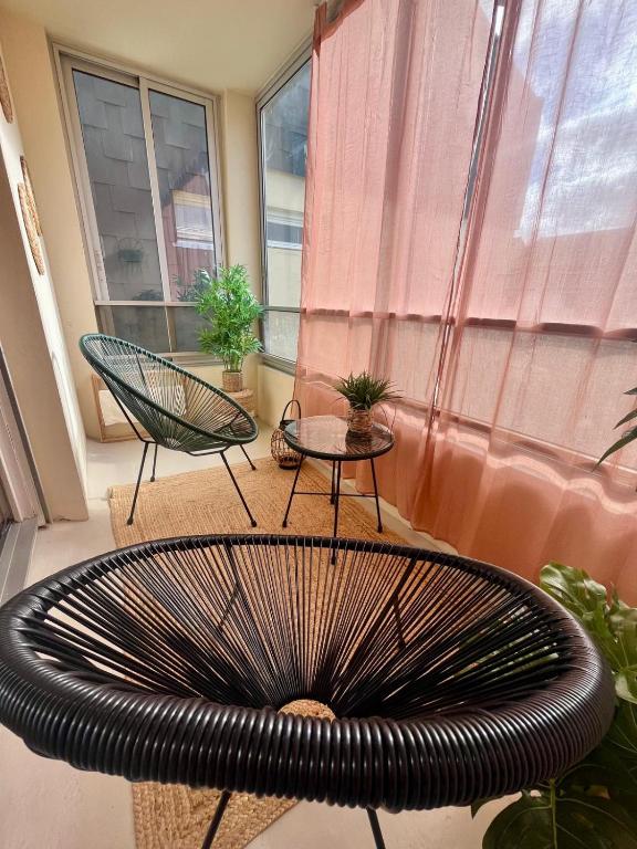 un banc dans une pièce avec deux chaises et une fenêtre dans l'établissement Serenity, appt avec loggia à 5min de la plage, à Courseulles-sur-Mer