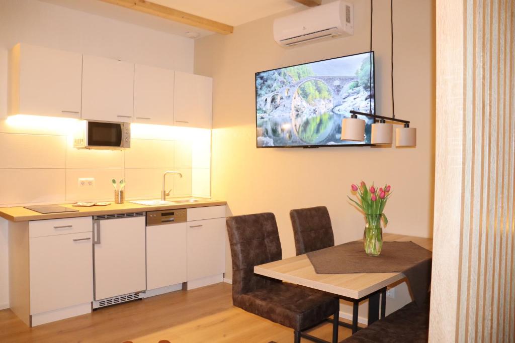a kitchen with a table and a tv on the wall at Ferienhaus mit Garten und Tor zur Dresdner Heide in Dresden
