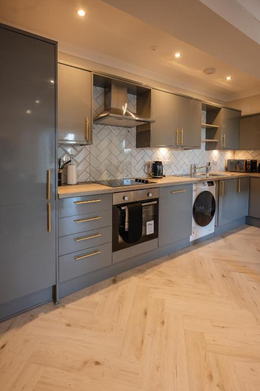 a kitchen with stainless steel appliances and wooden floors at Stirling Townhouse Apartment Btm in Stirling