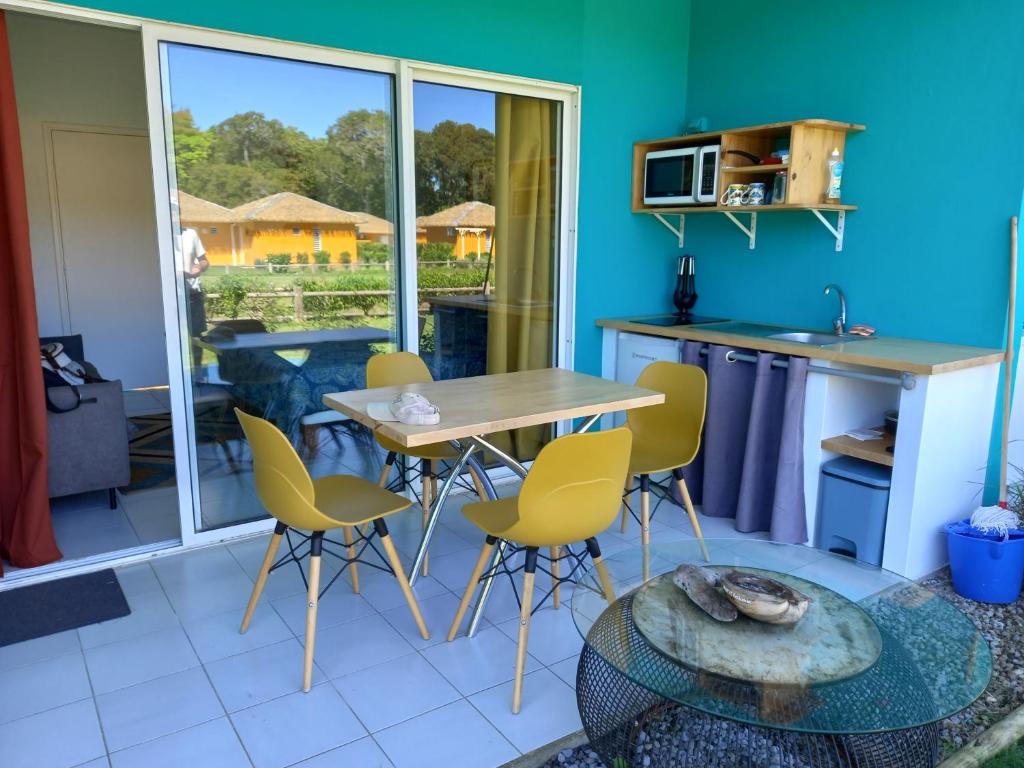 a kitchen with yellow chairs and a table and a counter at studio 105 hamaca grand bourg marie galante in Grand-Bourg
