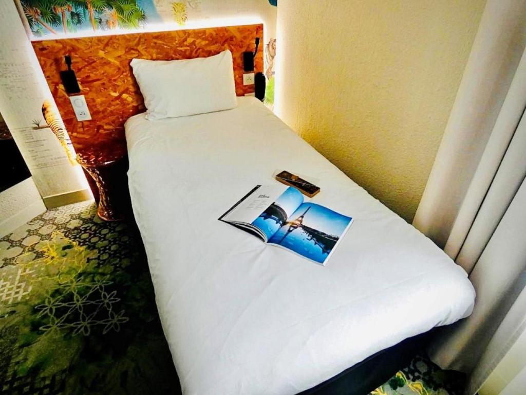 a bedroom with a white bed with a picture of a wedding at ibis Styles Paris Boulogne Marcel Sembat in Boulogne-Billancourt