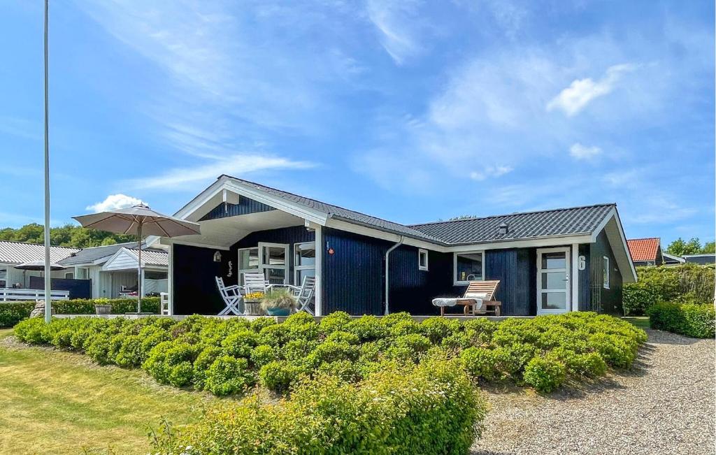 a blue house with a bench and an umbrella at Stunning Home In Sjølund With Kitchen in Sjølund