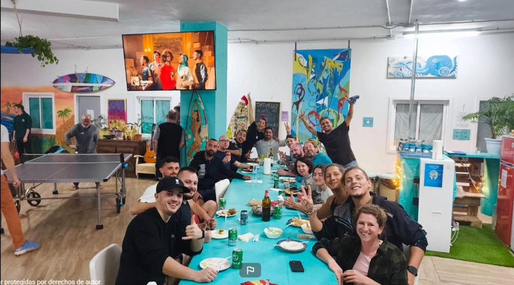 a group of people sitting at a long table at Medano Nest Hostel in El Médano