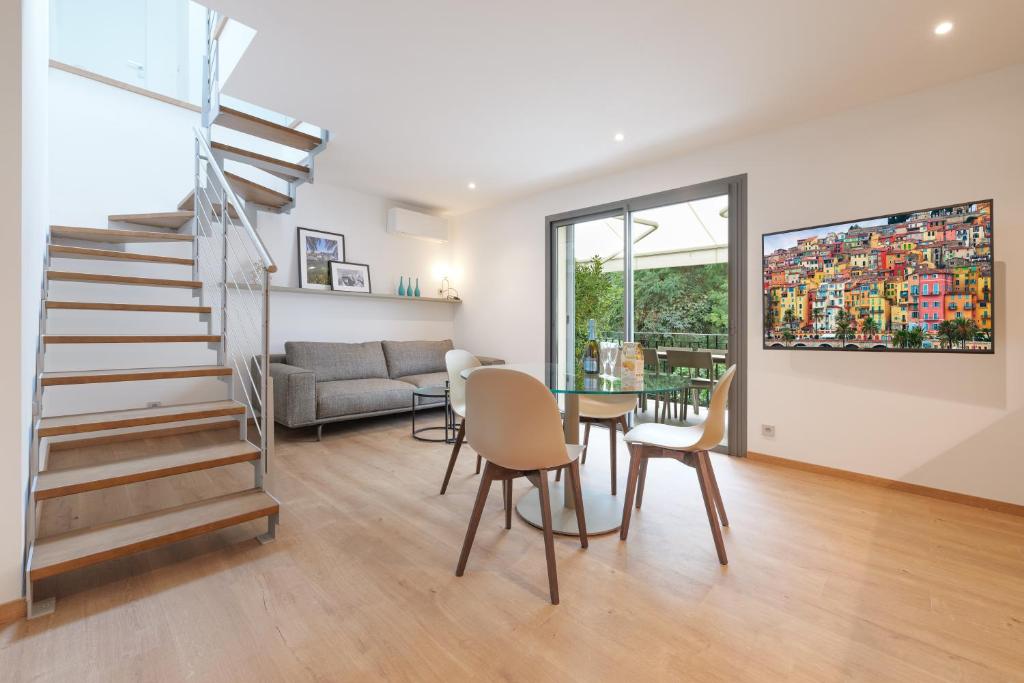 a living room with a staircase and a table and chairs at Villa Callista Mentone in Menton