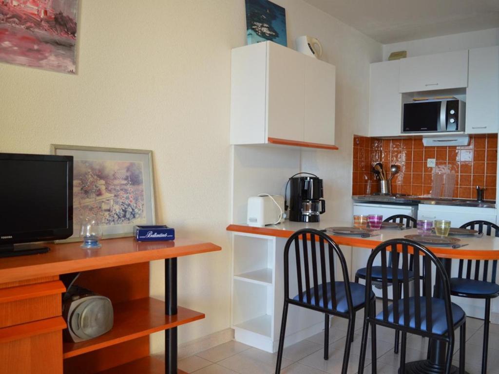 une cuisine avec des chaises et une table avec un comptoir dans l'établissement Studio cabine Banyuls 4 pers, vue mer, parking, WiFi - FR-1-225C-1, à Banyuls-sur-Mer