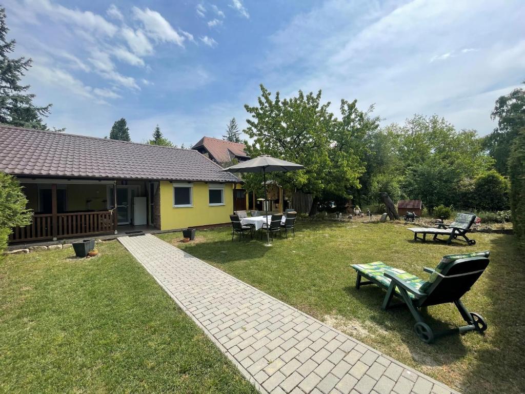 a yard with a house with a bench and a table at Veronica nyaralóház in Zamárdi