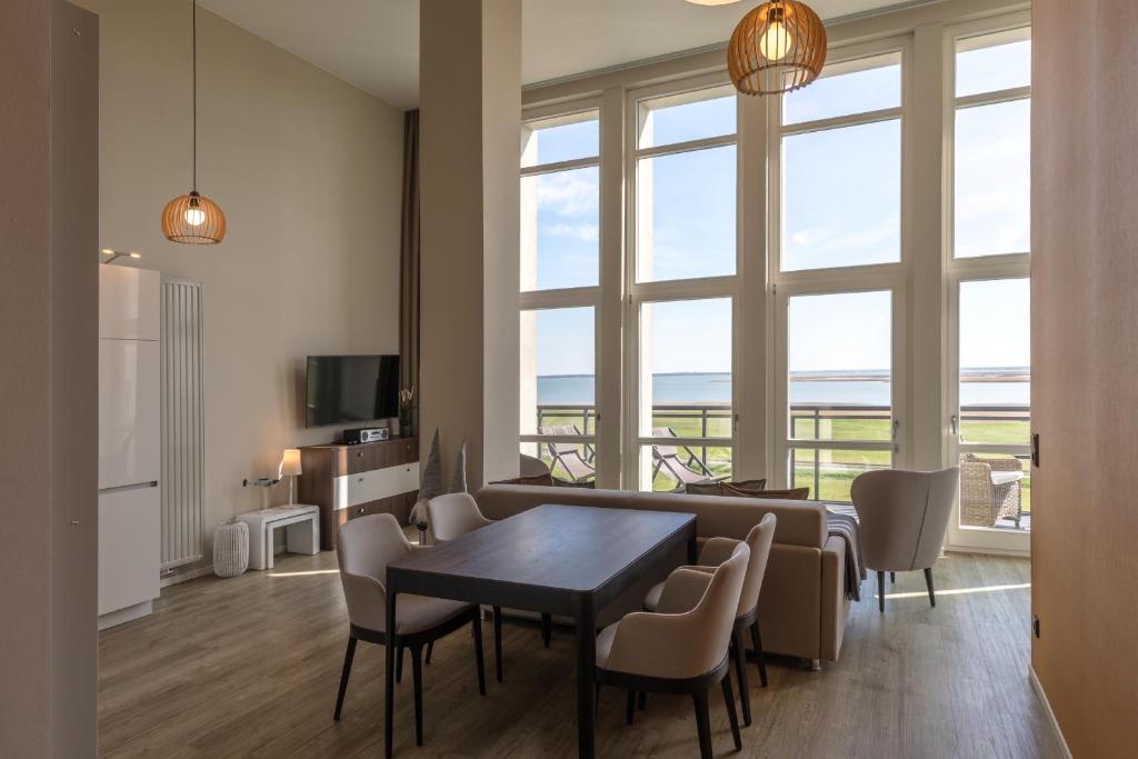 a living room with a table and chairs and a television at Mehr Meerblick - Stilvolle Ferienwohnung mit Panoramablick auf Ostsee und Saaler Bodden in Wustrow