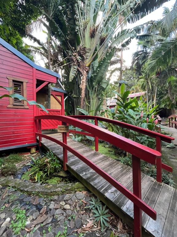 a red bench sitting on a wooden bridge at Le MORNE Aux F0US Cabanes & Jardin Tropical in Deshaies