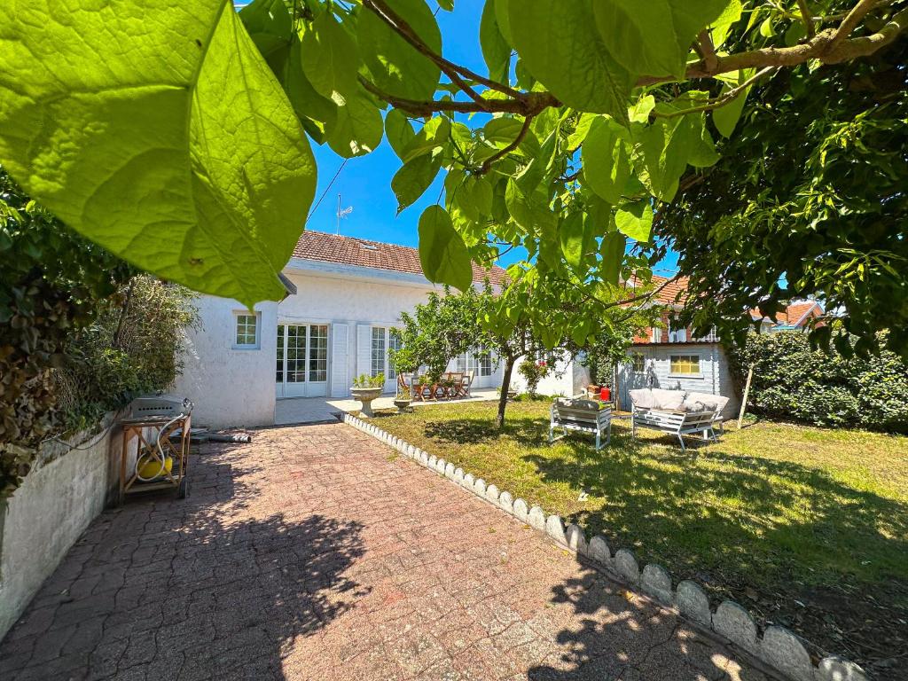 een huis met een stenen oprit voor een tuin bij Villa familiale proche Océan in Soulac-sur-Mer