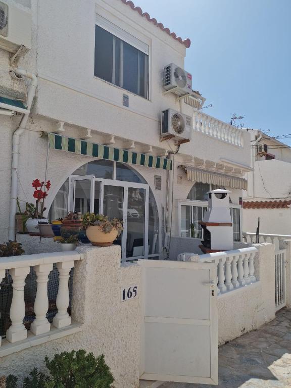a white house with a fence and a building at Bungalow con barbacoa in Torrevieja