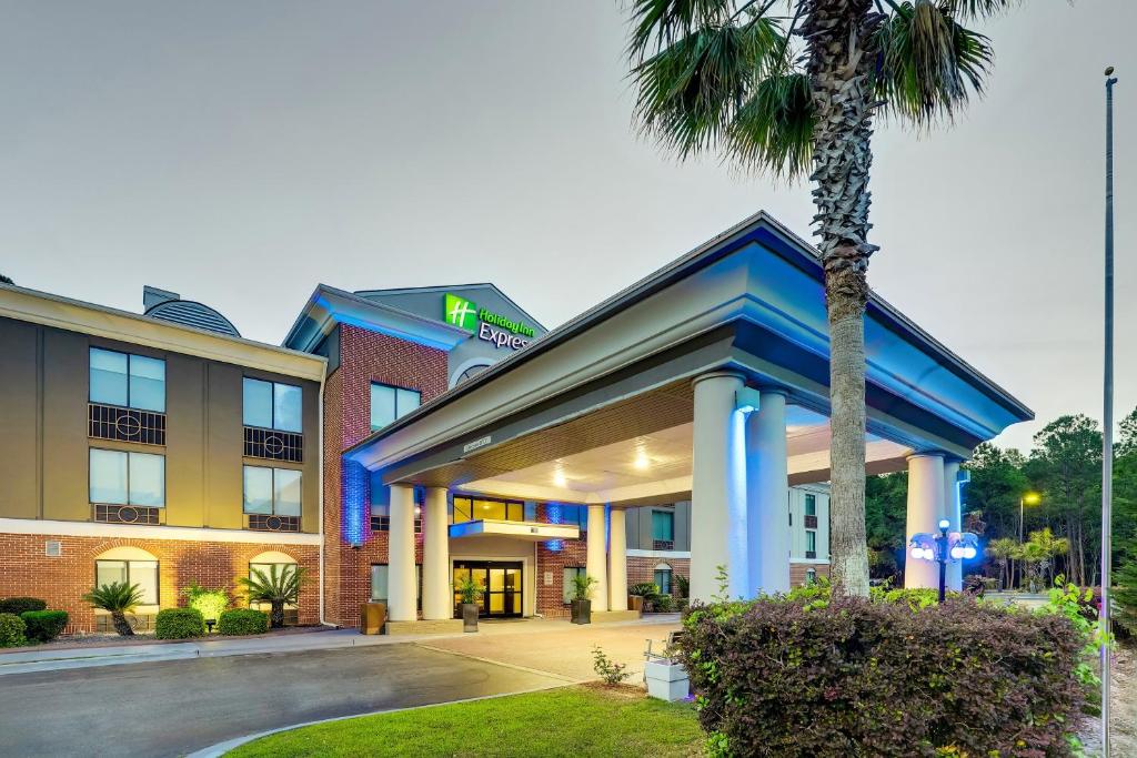 a hotel with a palm tree in front of it at Holiday Inn Express Hotel & Suites Hinesville by IHG in Hinesville