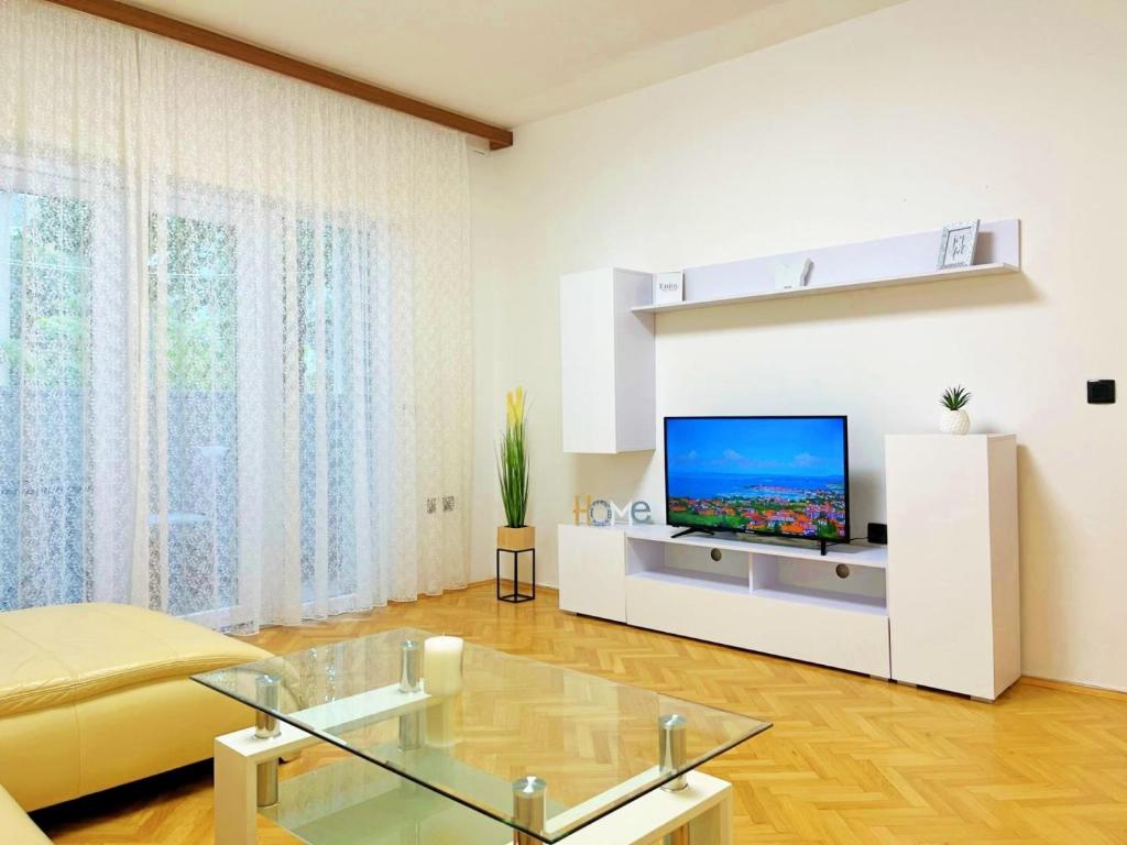 een woonkamer met een tv aan een witte muur bij Blue Dolphin in Rijeka