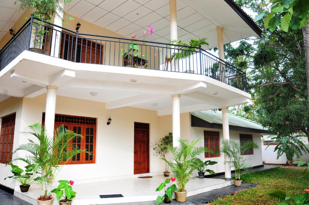 a white house with a balcony and plants at Anuradha Holiday Apartments in Anuradhapura