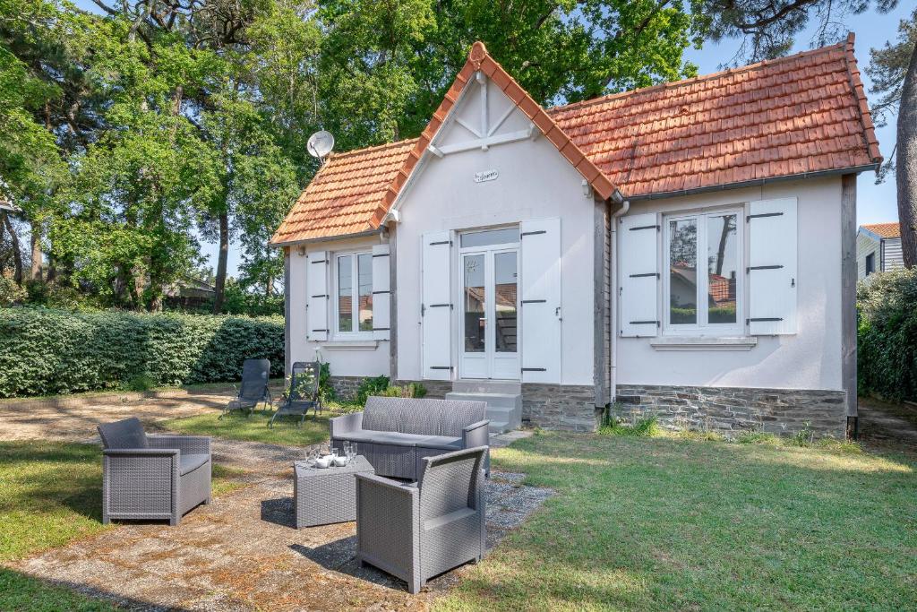 a small white house with chairs in a yard at Maison rénovée pour 8 - 200m Tharon plage in Tharon-Plage