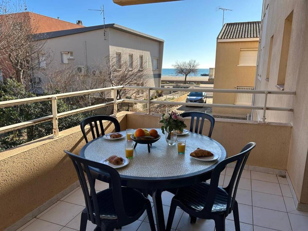 - une table et des chaises sur un balcon avec de la nourriture dans l'établissement Mass, à Valras-Plage