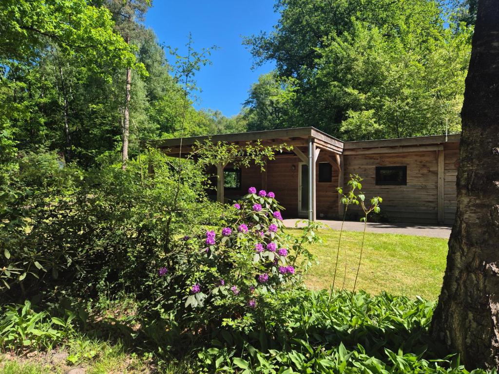 a log cabin in the woods with flowers at Boshuisje in Nutter
