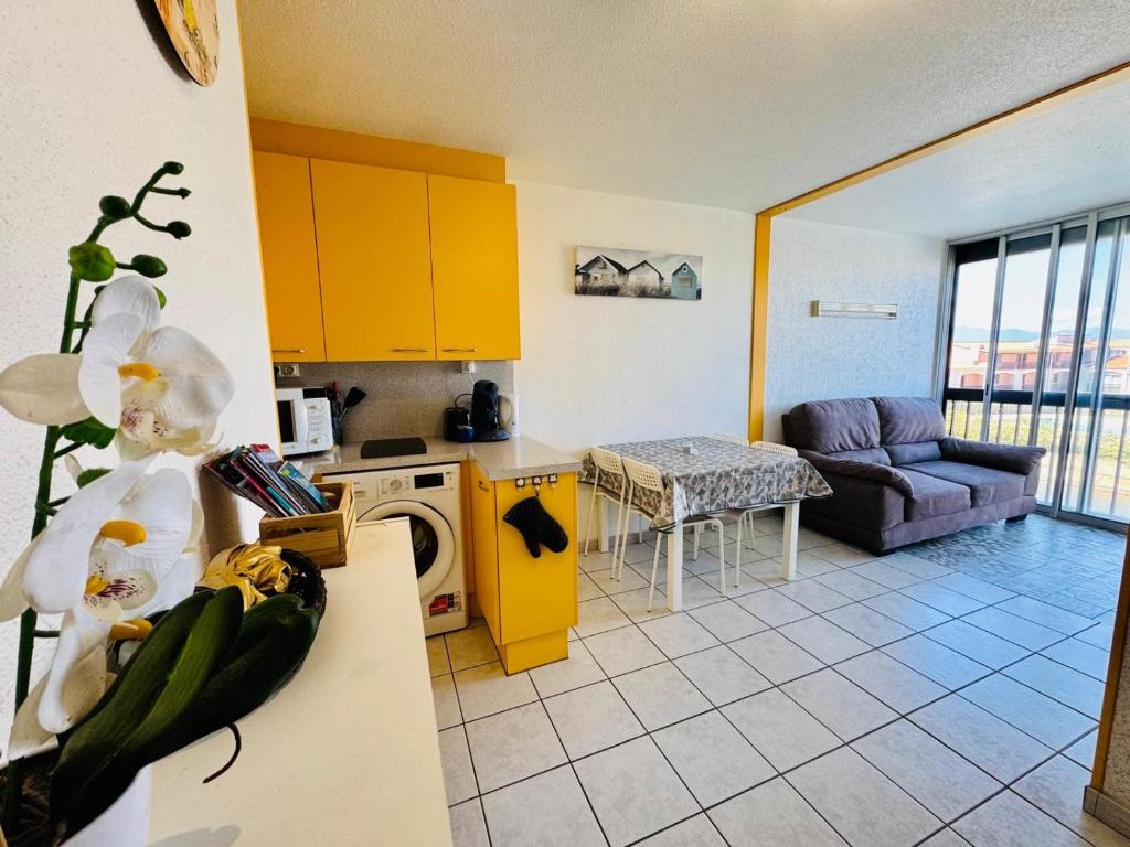 une cuisine avec des armoires jaunes et un salon dans l'établissement Escapade Marine Saint Cyprien, à Saint-Cyprien