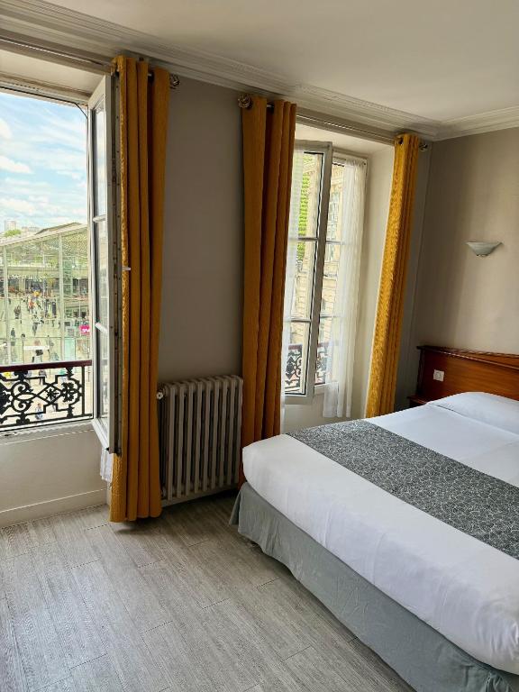a bedroom with a bed and a large window at New Hôtel Gare Du Nord in Paris