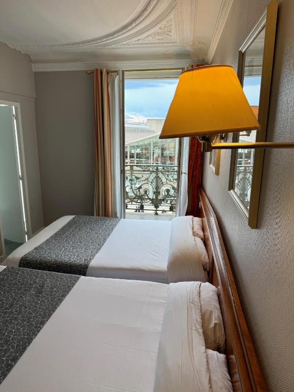 une chambre avec un lit avec une lampe et une fenêtre dans l'établissement Hotel Richmond Gare du Nord, à Paris