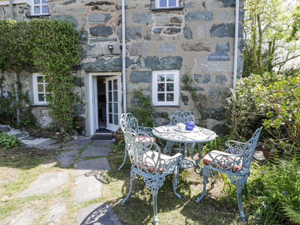 a table and chairs in front of a stone house at Pen Y Bryn Bach in Harlech