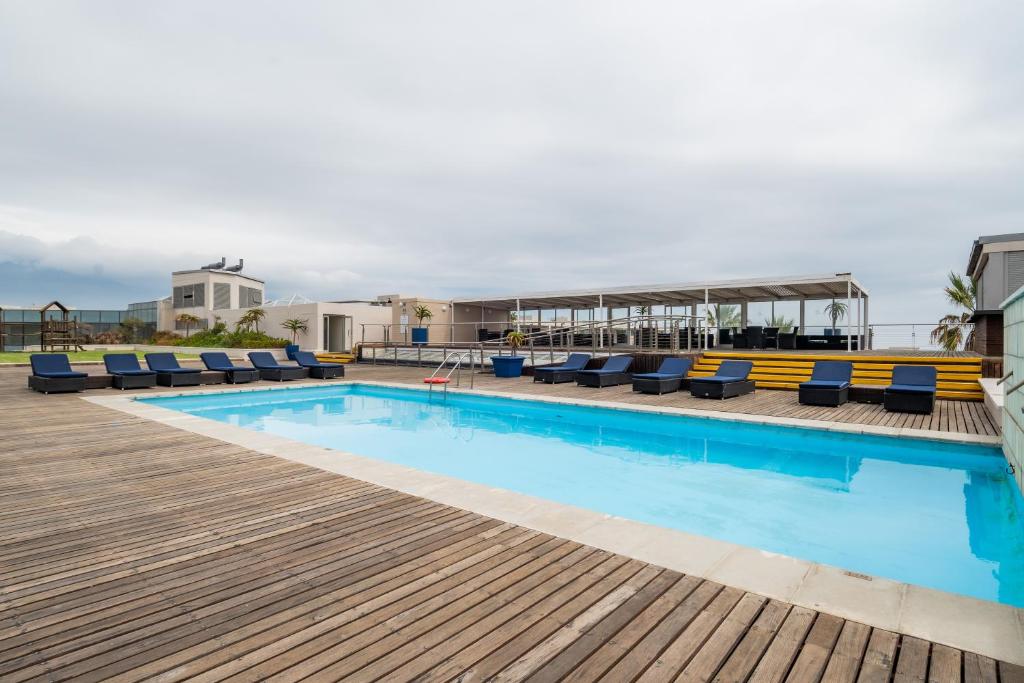 a swimming pool with lounge chairs on a deck at Lagoon Shoreline 2 Bedroom Apartment in Cape Town