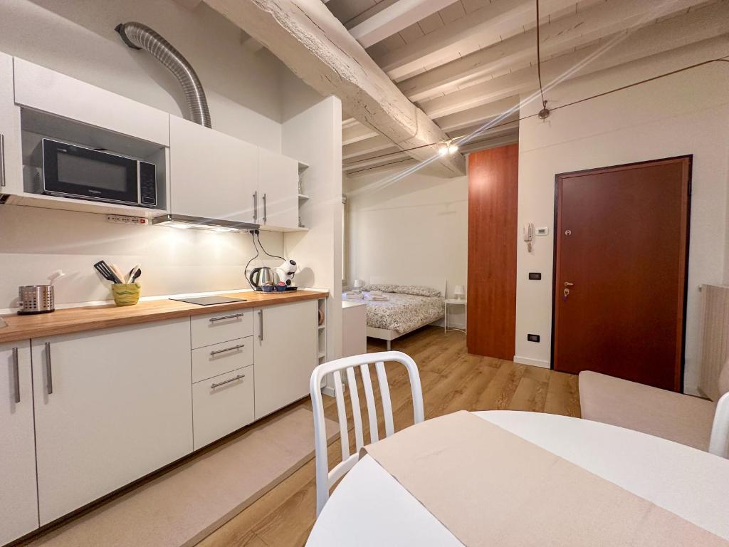 a kitchen with white cabinets and a table in a room at Margherita Home in Brescia