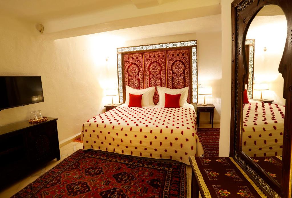 a bedroom with two beds and a large mirror at Riad Cherifa in Chefchaouene