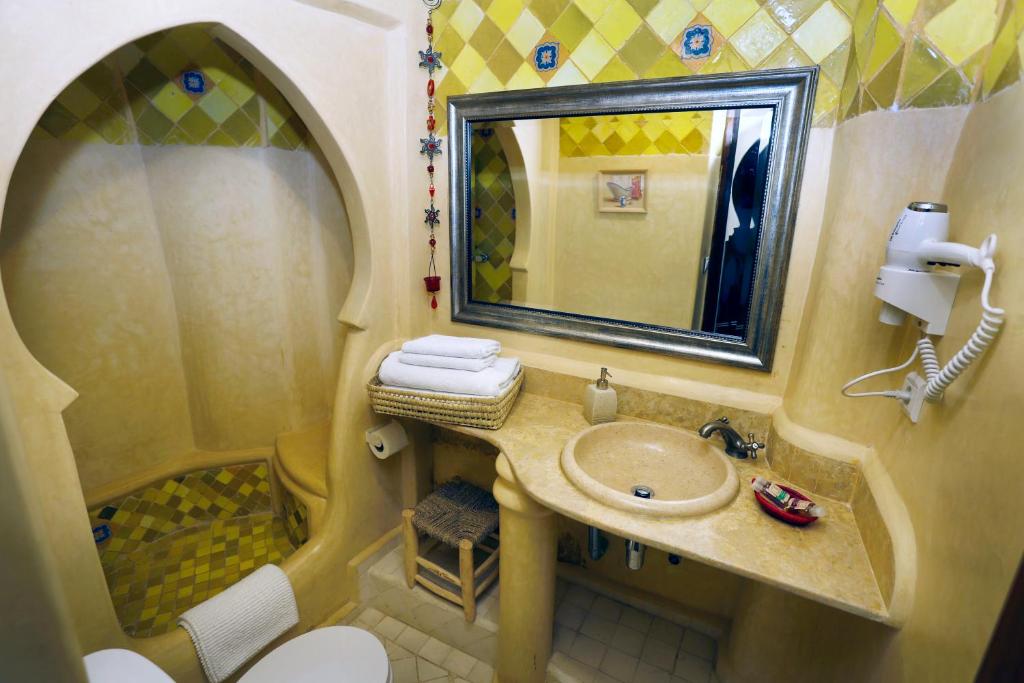 a small bathroom with a sink and a mirror at Riad Cherifa in Chefchaouene