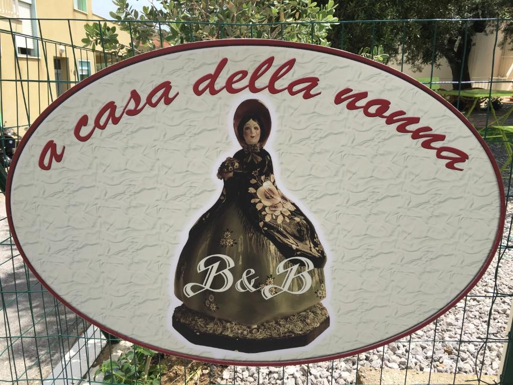 Ein Schild mit einer Frau in einem Kleid an einem Zaun. in der Unterkunft A Casa della Nonna in Cefalú