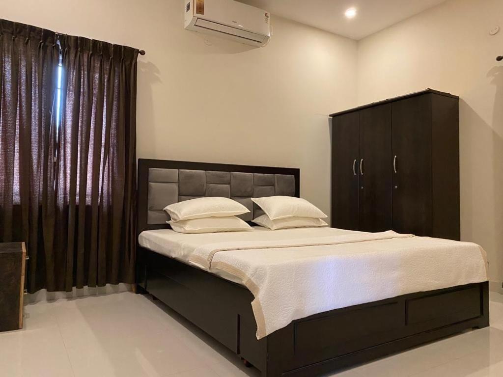 une chambre avec un grand lit avec des draps et des oreillers blancs dans l'établissement LBS Farmstay, à Alāndurai