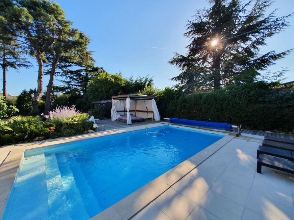 - une piscine dans une cour avec un banc et des arbres dans l'établissement Maison 8 personnes avec piscine chauffée en Ardèche Safari Peaugres, à Roiffieux