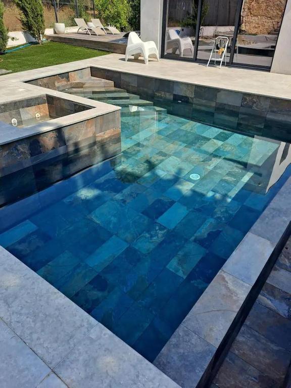 - une piscine d'eau bleue avec une chaise dans l'établissement 3 pièces MOUGINS dans villa contemporaine, à Mougins