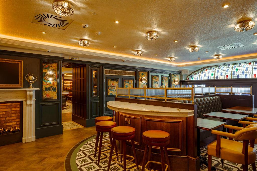 a restaurant with a bar with stools and a fireplace at The Mercantile Hotel in Dublin