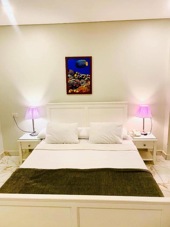 a bedroom with a large white bed with two lamps at Tiba Rose hurghada in Hurghada